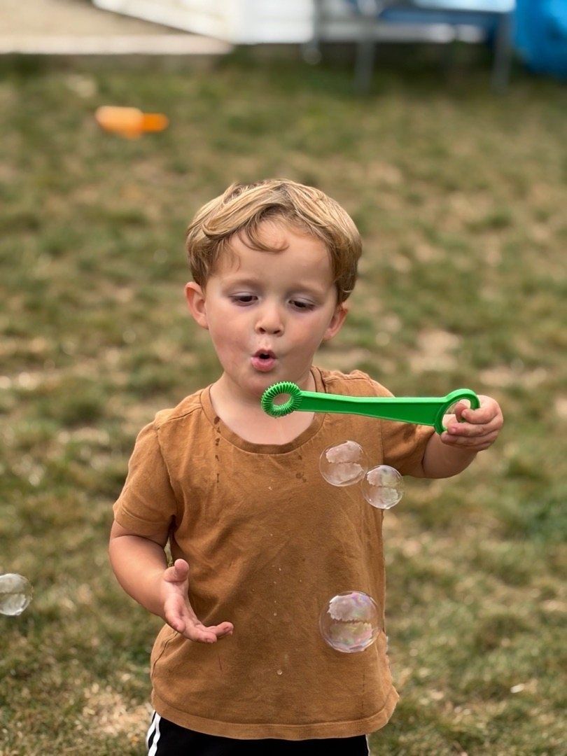 A boy blowing bubbles in the yard