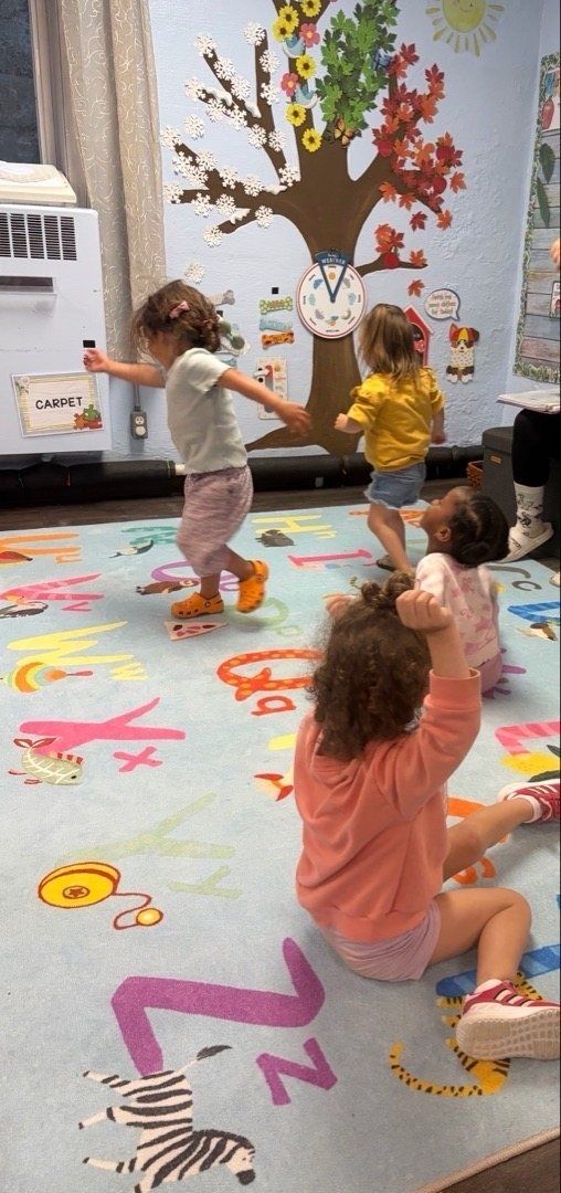 Kids dancing on an alphabet rug in a bright classroom