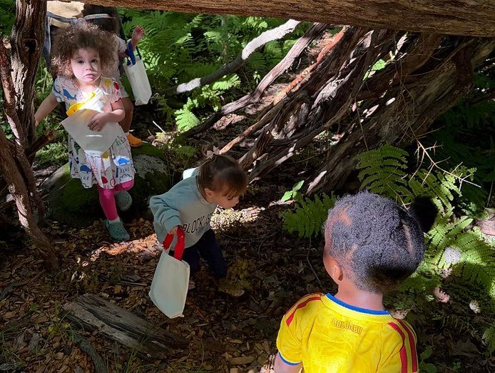 School-age kids exploring a stick shelter in the woods